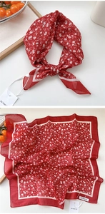 Detail showing red floral square scarf with lightweight texture and delicate stitching