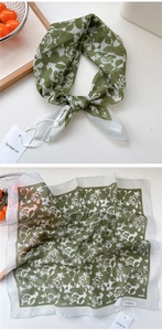 Macro detail of cotton-linen green floral scarf with fine stitched edges and tag