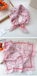 Close-up of pink silk scarf with cherry and daisy prints on a white background
