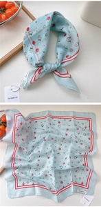 Detail of light blue cotton linen scarf with red cherry and daisy patterns and tag