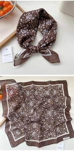Detail of a dark brown floral silk scarf with small white flowers and branded tag