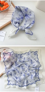 Detail of blue floral cotton linen scarf with wavy edges and brand tag for styling