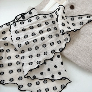 Close-up of retro beige polka dot cotton linen neckerchief with black wavy lettuce edges