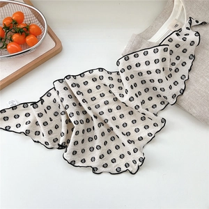 Detailed view of polka dot cotton scarf with decorative ruffle edges and woven texture