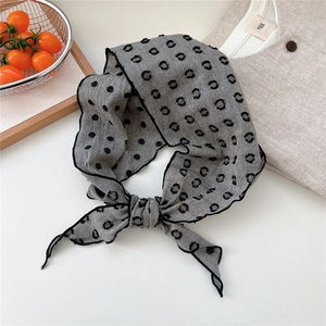 Detail of grey polka dot cotton linen neckerchief tied in a bow with fine black edging