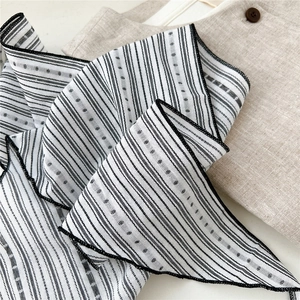 Detailed close-up of striped cotton linen scarf with black patterns on beige fabric