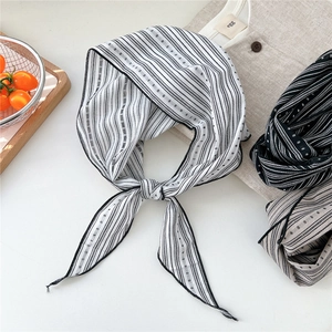 Detailed view of striped and polka dot cotton-linen scarf on a natural linen background