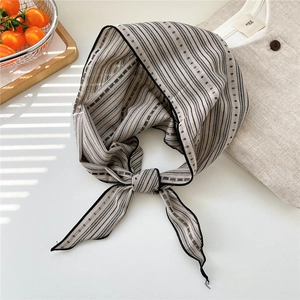 Detail of striped polka dot cotton linen neck scarf with delicate black hem on white desk