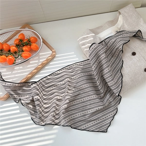 Detail of striped cotton linen neck scarf with lettuce edge on beige linen shirt