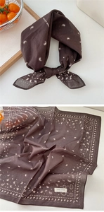 Macro shot of a dark brown paisley cotton bandana showing fabric texture and 100% cotton label