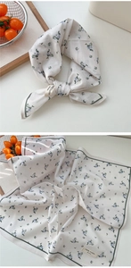 Détail d'un petit foulard carré en coton avec imprimé floral bleu et bord vert