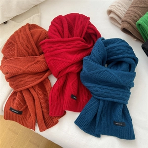 Close-up of thick cable knit wool scarves with 100% wool label in vibrant colors