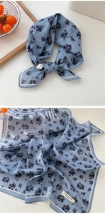 Détail d'un foulard en coton bleu à fleurs avec rayures blanches et texture délicate