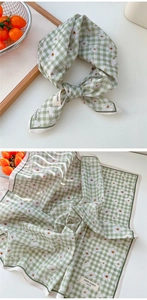 Détail d'un petit foulard en coton à carreaux verts avec des motifs marguerites