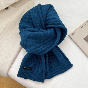 Detail of blue wool scarf showing heavy cable knit texture and 100% WOOL label
