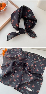 Détail macro d'un foulard en coton respirant avec imprimé cerise rouge sur tissu noir