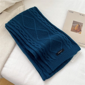 Detail of 100% wool knitted scarf with intricate navy blue cable and diamond patterns