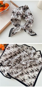 Gros plan d'un foulard en coton à motif floral rétro rose avec étiquette de marque cousue