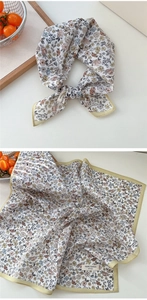 Détail d'un foulard floral en coton avec bordure jaune et étiquette 100% coton