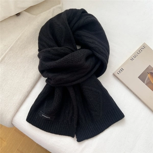 Detail of 100% wool black scarf with thick knit texture and ribbed edge finish