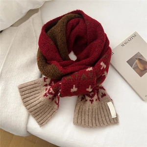 Detail of red and brown knit scarf featuring Nordic snowflake jacquard and soft texture