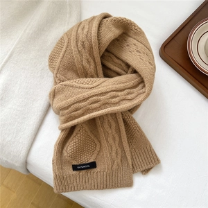 Close-up of camel wool scarf showing premium cable knit texture and 100% wool label