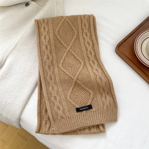 Detail of camel wool scarf showing diamond knit pattern and 100% wool label