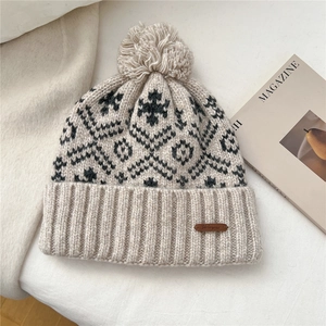 Detailed knit texture and leather brand label on a snowflake pattern winter pom hat
