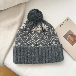 Detail of grey snowflake knit beanie with a large pompom and thick ribbed cuff