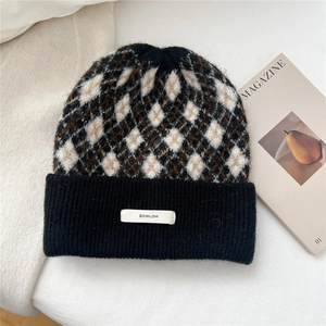 Detail of diamond pattern knit beanie with logo tag on ribbed cuff for winter warmth