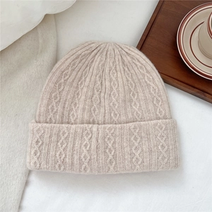 Close-up of beige wool knitted hat featuring intricate diamond and cable stitch textures