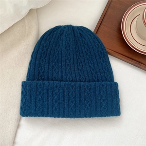 Detail of dark blue knit wool hat featuring thick cable knit texture and folded cuff
