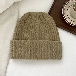 Detailed close-up showing the chunky cable knit texture and khaki wool of the winter beanie