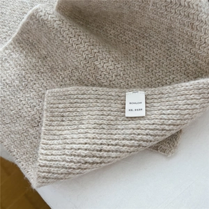 Dettaglio della trama della sciarpa in misto lana beige con morbidi dettagli in maglia