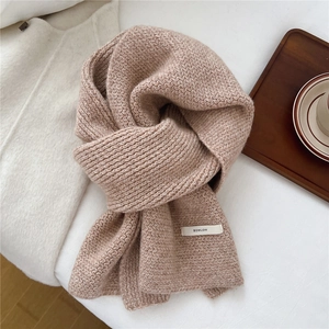 Dettaglio della sciarpa in maglia beige misto lana con etichetta del marchio BOWLOW