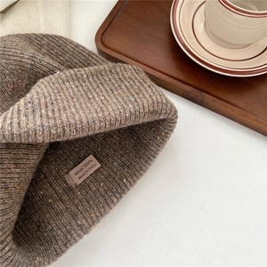 Detailed view of dark brown knitted hat made of 100% wool with colorful fiber specks