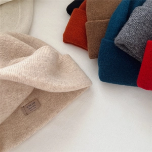 Close-up of 100% wool knitted beanies showing various colors and a fabric brand label
