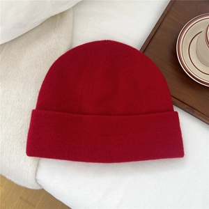 Detailed knit texture of solid red wool beanie for winter warmth on white fabric