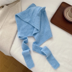 Detail of light blue knit balaclava showing soft texture and long ties on white fabric
