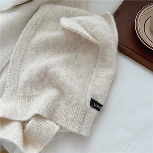 Chic beige knitted ear protection hat with plush texture and woven label for winter warmth
