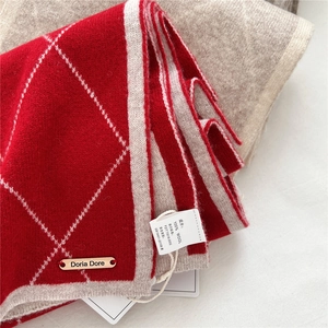Macro shot of red and white diamond pattern wool scarf with 100% wool material tag