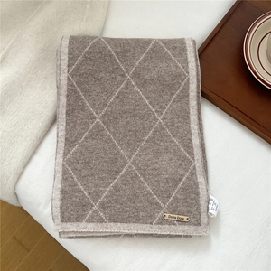 Detail of coffee and beige checkered wool knit scarf with a small metal logo tag