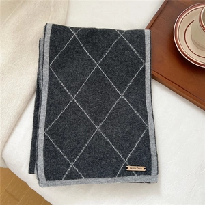 Close-up of diamond pattern knit scarf with branded label on soft warm fabric