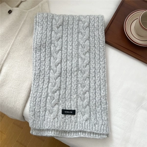 Detailed texture of cable knit wool blend scarf with minimalist logo tag in grey