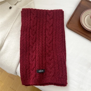 Macro shot of deep red cable knit wool scarf texture with brand label on white fabric