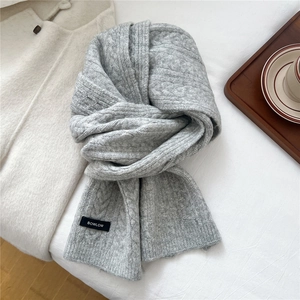 Close-up of light gray wool blend knit scarf with cable patterns and brand label