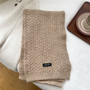 Macro detail of light brown chunky cable knit wool scarf texture with branding label