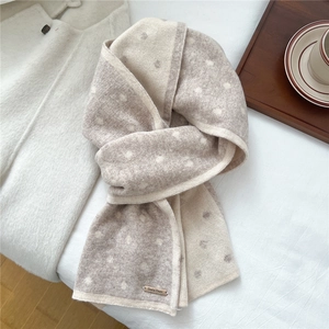 Dettaglio della calda sciarpa di lana a maglia con motivo a pois beige e marrone e texture