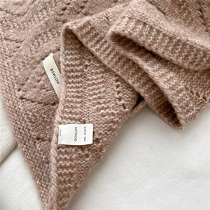 Close-up of soft light brown wool blend knit texture and detail of the brand label