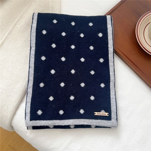 Dettaglio della sciarpa di lana blu navy a pois con bordi grigi e targhetta dorata